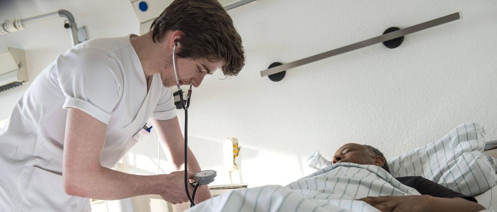 Ein Krankenpflegeschüler misst den Blutdruck eines Patienten.