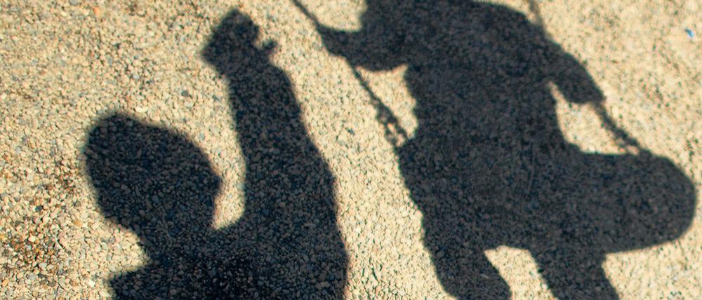 Der Schatten von einem Mann und einem Kind auf der Schaukel.