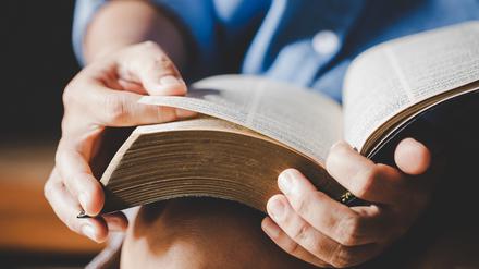 Eine Bibel wird in den Händen gehalten.