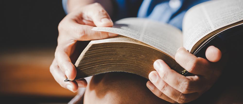 Eine Bibel wird in den Händen gehalten.