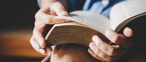 Eine Bibel wird in den Händen gehalten.