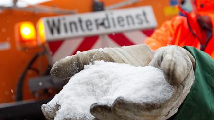 Ein Mitarbeiter des Räumdienstes hält Streusalz in der Hand.