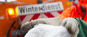 Ein Mitarbeiter des Räumdienstes hält Streusalz in der Hand.