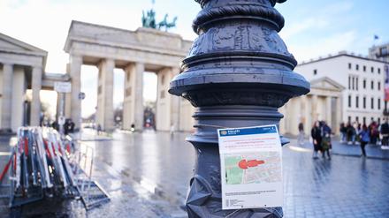 Ein Schild der Polizei mit dem rot markierten Sicherheitsbereich rund um den Pariser Platz und dem Brandenburger Tor hängt an einem Laternenpfahl. 