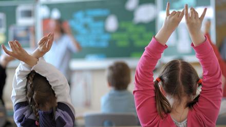 Zwei Schülerinnen melden sich während des Unterrichts in einem Klassenzimmer der Grundschule.