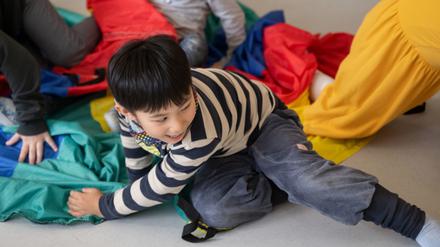 13.03.2023, Baden-Württemberg, Kornwestheim: Kinder einer Kindergartengruppe der Kita Hoppsala nehmen in einem Gruppenraum an einer Bewegungseinheit teil. Seit Sommer 2020 gibt es für Kitas die Möglichkeit, Inhouse-Fortbildungen zur Bewegungsförderung, finanziert durch das Kultusministerium und organisiert durch die Kinderturnstiftung Baden-Württemberg, zu buchen. Dieses Angebot soll nun mit Unterstützung der Unfallkasse Baden-Württemberg vertieft werden. Foto: Marijan Murat/dpa - ACHTUNG: Nur zur redaktionellen Verwendung im Zusammenhang mit der aktuellen Berichterstattung und nur mit vollständiger Nennung des vorstehenden Credits +++ dpa-Bildfunk +++