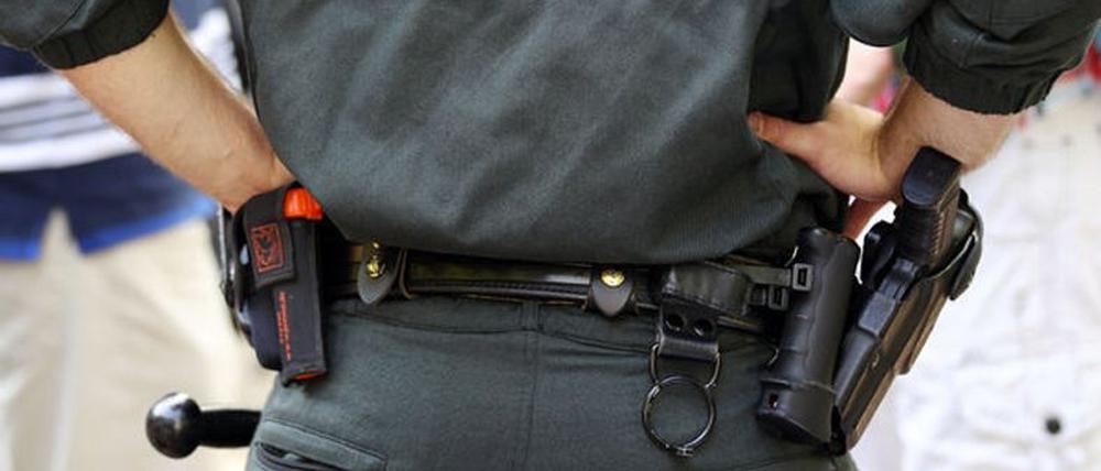 Ein Polizist trägt Handschellen, Pistole, Schlagstock und eine Schutzweste.