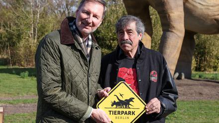 30.03.2023, Berlin: Andreas Knieriem (l), Direktor Berliner Zoo und Tierpark, und Don Lessem, Buchautor,  Dinosaurier-Experte und wissenschaftlicher Berater der Ausstellung, eröffnen die Dinoworld Berlin im Tierpark Berlin. Bis Oktober können Besucher im Tierpark Berlin-Friedrichsfelde die Ausstellung mit rund 23 lebensgroßen Dinosauriern besuchen. Die neue Pfad ist ab heute für alle Besucher begehbar. Foto: Gerald Matzka/dpa +++ dpa-Bildfunk +++