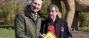 30.03.2023, Berlin: Andreas Knieriem (l), Direktor Berliner Zoo und Tierpark, und Don Lessem, Buchautor,  Dinosaurier-Experte und wissenschaftlicher Berater der Ausstellung, eröffnen die Dinoworld Berlin im Tierpark Berlin. Bis Oktober können Besucher im Tierpark Berlin-Friedrichsfelde die Ausstellung mit rund 23 lebensgroßen Dinosauriern besuchen. Die neue Pfad ist ab heute für alle Besucher begehbar. Foto: Gerald Matzka/dpa +++ dpa-Bildfunk +++