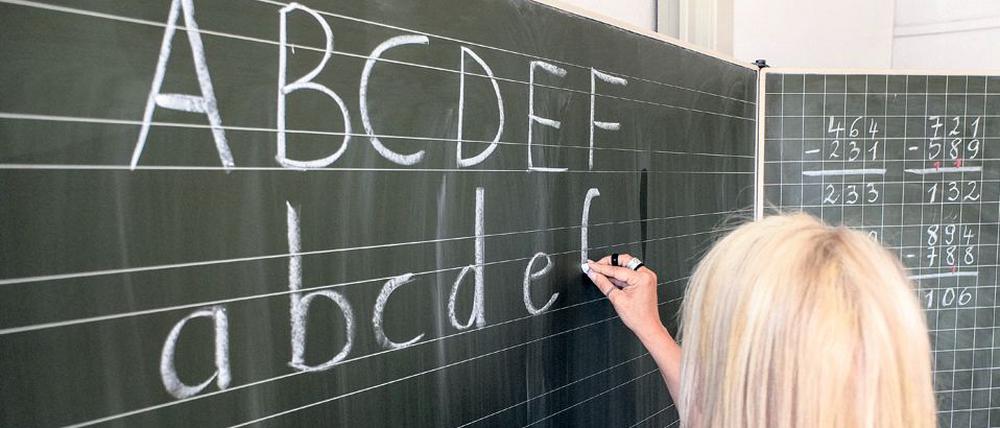 ARCHIV - ILLUSTRATION - Eine Grundschullehrerin schreibt am 15.06.2015 in Hamburg die ersten Buchstaben des Alphabets auf eine Schultafel in einem Klassenzimmer. Foto: Axel Heimken/dpa (zu dpa «Volle Klassenzimmer, wenig Lehrer - Schuljahr startet mit Kritik». 17.09.2015) +++(c) dpa - Bildfunk+++