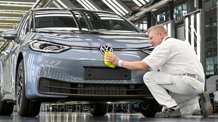 Ein VW-Techniker arbeitet an der finalen Inspektion eines E-Autos.
