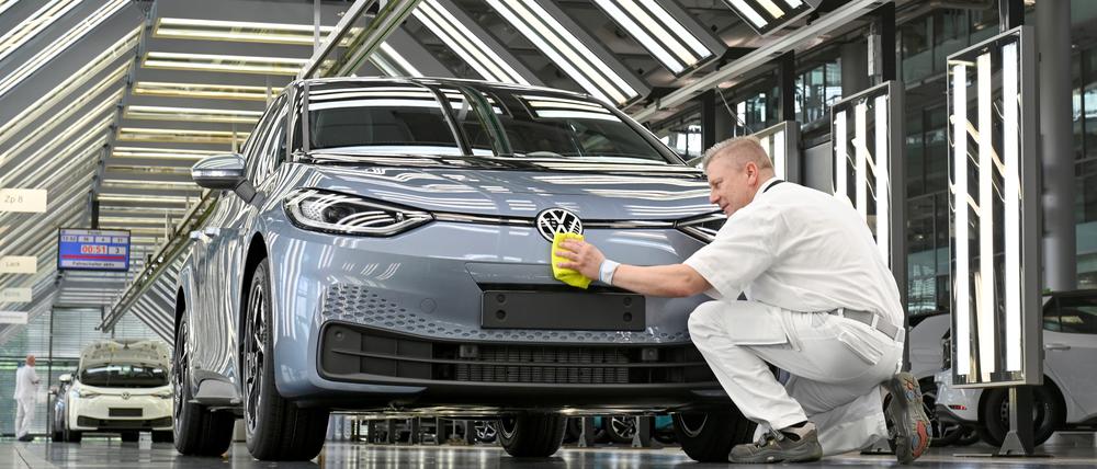 Ein VW-Techniker arbeitet an der finalen Inspektion eines E-Autos.