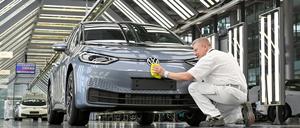 Ein VW-Techniker arbeitet an der finalen Inspektion eines E-Autos.