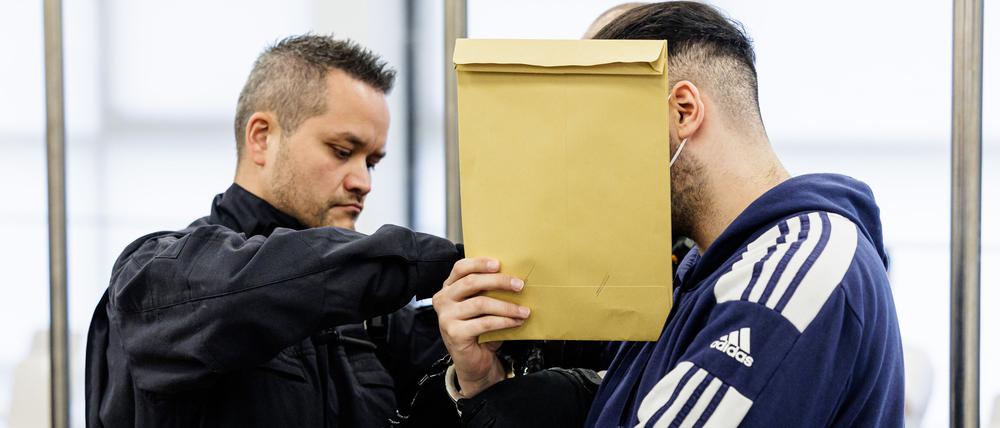 Der Angeklagte Abdul Majed R.  (r) wird von Justizbeamten in Handschellen in den Gerichtssaal des Oberlandesgerichts Dresden geführt.