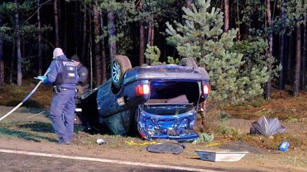 01.04.2023, Brandenburg, Joachimsthal: Polizisten arbeiten an einem Wrack. Zwei Menschen sind bei dem Autounfall auf der L23 zwischen Joachimsthal und Friedrichswalde (Landkreis Barnim) schwer verletzt worden. 