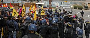 Mitglieder französischer Gewerkschaften und Umweltaktivisten stehen Polizeikräften gegenüber, als sie vor der Ankunft des französischen Präsidenten Macron demonstrieren.