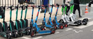 E-Scooter von drei verschiedenen Anbietern stehen auf einem dafür vorgesehenen Parkplatz.