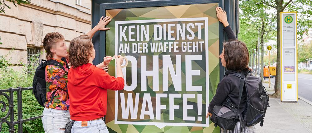 Frida Henkel (M) klebt mit Sympathisantinnen ein Plakat der Bundeswehr mit dem von ihr abgeänderten Slogan «Kein Dienst an der Waffe geht ohne Waffe!» vor dem Kriminalgericht in Moabit an.