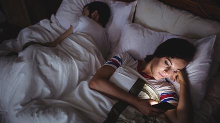Woman using mobile phone while lying on bed at bedroom