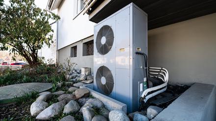 Die Lüftungsanlage einer Wärmepumpe steht vor einem Wohnhaus.