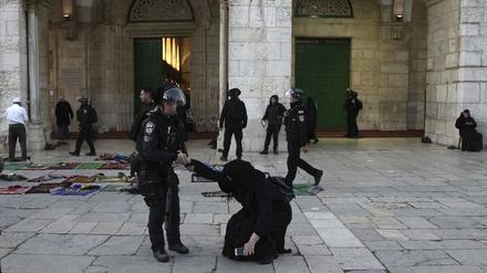 Eine israelische Polizistin zieht eine Gläubige hoch, die auf dem Gelände der Al-Aqsa-Moschee während des muslimischen heiligen Monats Ramadan in der Altstadt von Jerusalem auf dem Boden saß.