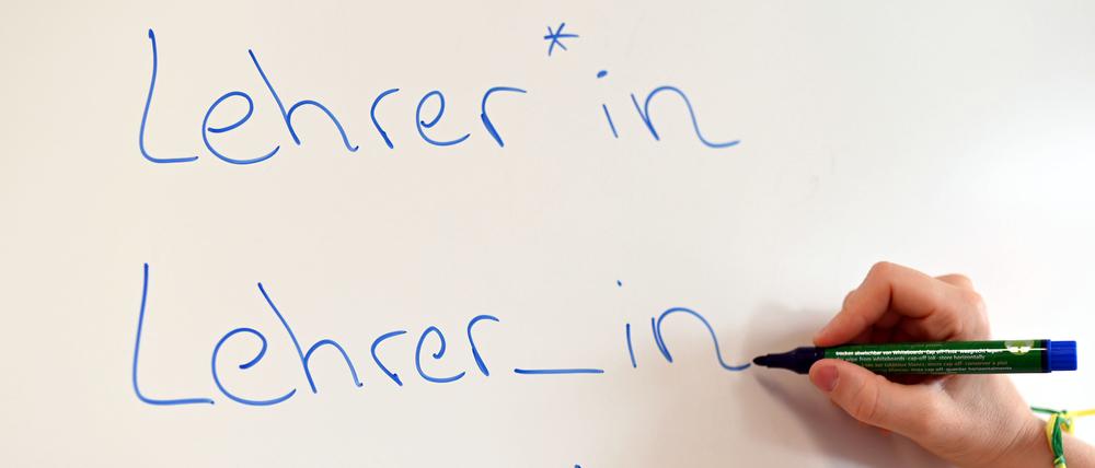 An einem Whiteboard steht das Wort Lehrer in verschiedenen Gender-Schreibweisen. 