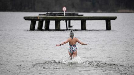 Eine Frau wagt sich ins kalte Wasser des Wannsees. 