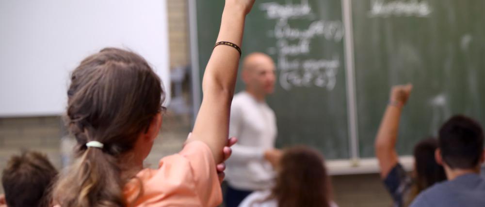 Eine Schülerin der fünften Klasse hebt im Unterricht den Finger. Foto: Daniel Karmann/dpa