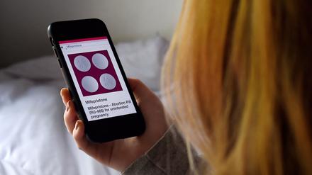 Eine Frau schaut sich die Website von Mifepriston auf dem Handy an.
