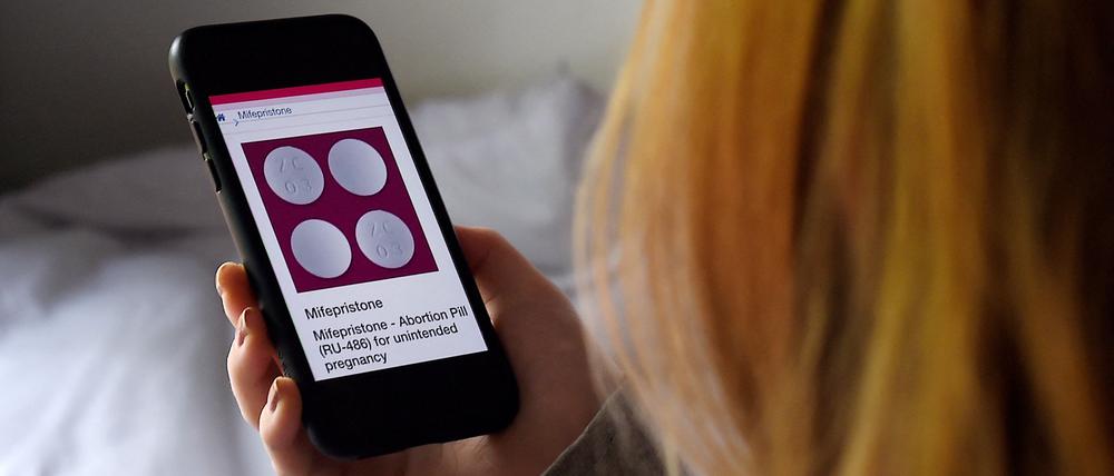 Eine Frau schaut sich die Website von Mifepriston auf dem Handy an.