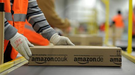 Ein Mitarbeiter der Versandabteilung des Amazon Logistikzentrums in Pforzheim (Baden-Württemberg) legt am 11.12.2012 ein fertig verpacktes Paket auf ein Fließband. 