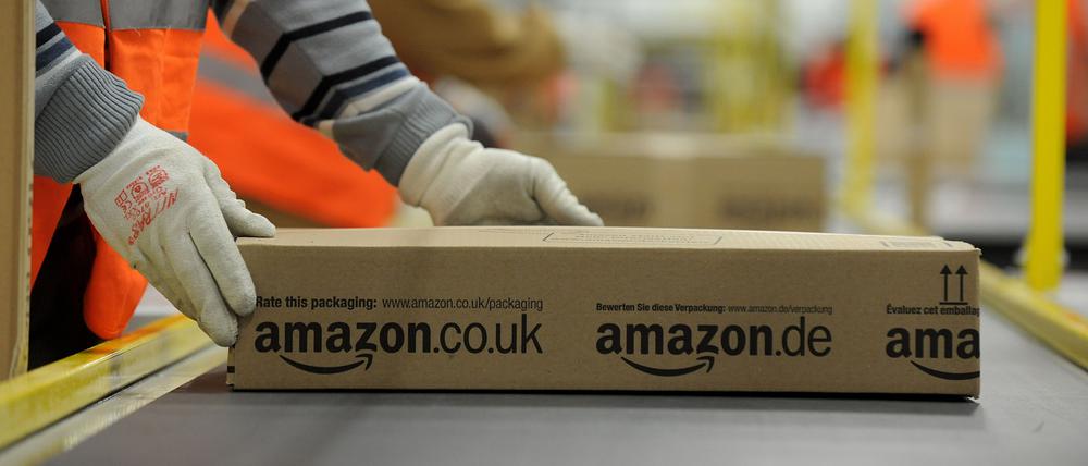 Ein Mitarbeiter der Versandabteilung des Amazon Logistikzentrums in Pforzheim (Baden-Württemberg) legt am 11.12.2012 ein fertig verpacktes Paket auf ein Fließband.