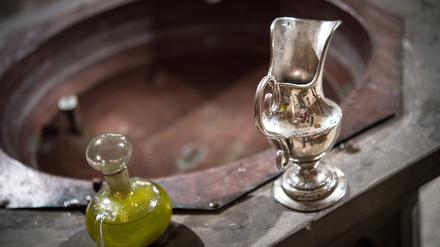Eine Wasserkaraffe und Chrisamöl in einem Glasflakon stehen am Rande des Taufbeckens bereit. 