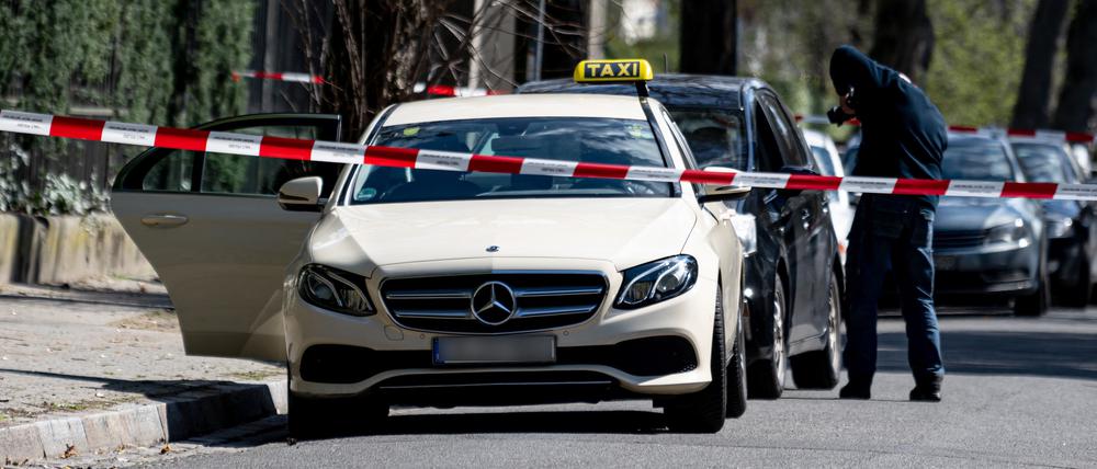 Mitarbeiter der Berliner Polizei steht vor einem Taxi in Berlin-Grunewald. Am Donnerstagmorgen gab in der Brahmsstraße es einen tätlichen Angriff auf den Fahrer des Taxis.