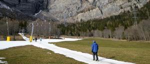 Skifahrer benutzen einen Lift auf einer künstlich beschneiten Skipiste in der Schweiz.