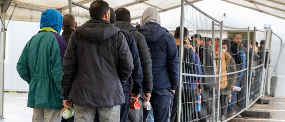 In der Landeserstaufnahmestelle warten Flüchtlinge in einer Schlange vor der Essensausgabe.