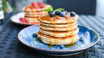 Pancake-Turm unter Blaubeeren und Sirup.
