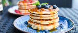 Pancake-Turm unter Blaubeeren und Sirup.