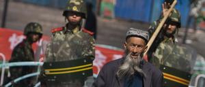 Ein Angehöriger der uigurischen Minderheit in China geht in Ürümqi in der Unruheregion Xinjiang vorbei an chinesischen Sicherheitskräften.