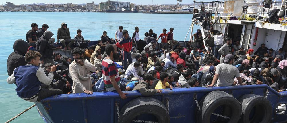 Migranten warten im sizilianischen Hafen von Catania von Bord eines Schiffes zu gehen.