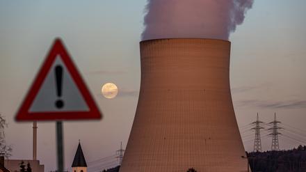 Wasserdampf steigt aus dem Kühlturm des Kernkraftwerks Isar 2 hinter einem Warnschild.