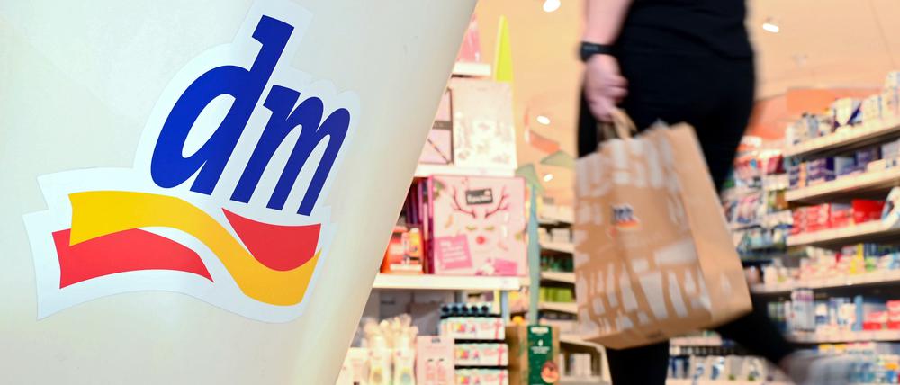 Eine Person geht in einer Filiale der Drogeriemarktkette dm mit einer Einkaufstüte am Kassenbereich vorbei.