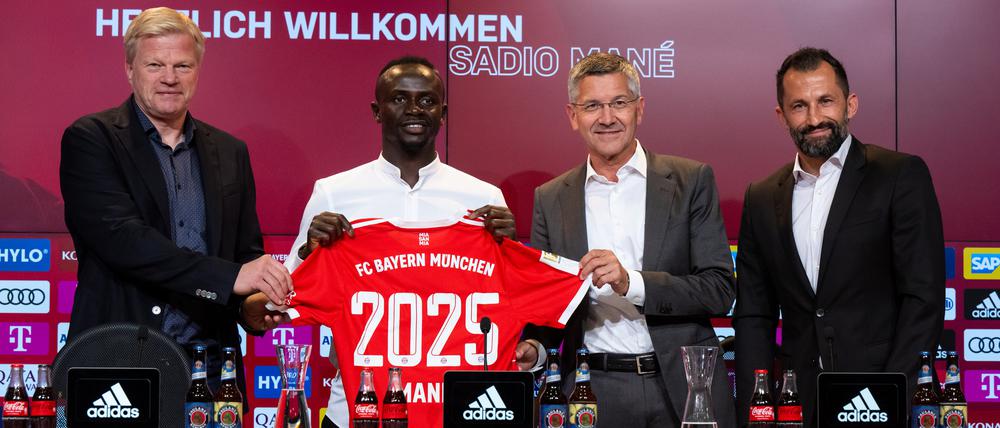 Oliver Kahn, Vorstandsvorsitzender der FC Bayern München AG, Sadio Mane, Herbert Hainer, Präsident von München, und Hasan Salihamidzic, Sportdirektor von München,(v.l.-r.) stehen nach der Vorstellung mit einem Trikot für ein Foto zusammen.