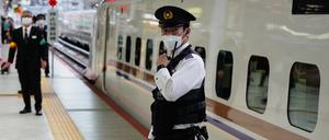 Uniformierte Mitarbeiter der Central Japan Railway Company stehen kurz vor der Abfahrt des Zuges nach Karuizawa neben dem Shinkansen-Hochgeschwindigkeitszug.