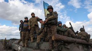 Ukrainian soldiers pose atop a personnel armoured carrier on a road near Lyman, Donetsk region on October 4, 2022, amid the Russian invasion of Ukraine. - Ukraine's President Volodymyr Zelensky said on October 2, 2022 that Lyman, a key town located in one of four Ukrainian regions annexed by Russia, had been "cleared" of Moscow's troops. (Photo by Anatolii Stepanov / AFP)