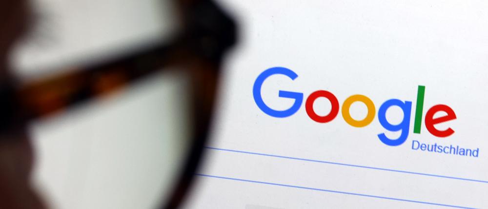 Die Seite der Suchmaschine von Google ist hinter einer Frau mit Brille zu sehen.