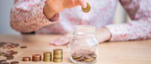 Eine Frau wirft Münzen in ein Glas. Ende Oktober rufen die Banken wieder zum Weltspartag auf.