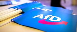 Fähnchen mit dem Logo der AfD liegen beim Landesparteitag der AfD Bayern auf einem Tisch.