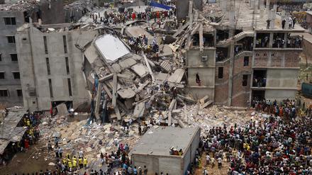 Rettungskräfte stehen auf den Resten einer  zusammengestürzten Fabrik in Bangladesh. Bei dem Einsturz des Gebäudes am 24. April 2013 kamen mehr als 1100 Menschen ums Leben. 