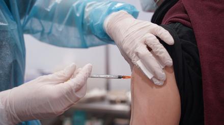Ein junger Mann wird mit einer Booster-Dosis eines Corona-Impfstoffs im Impfzentrum in der Potsdamer Schinkelhalle gegen das Coronavirus geimpft.